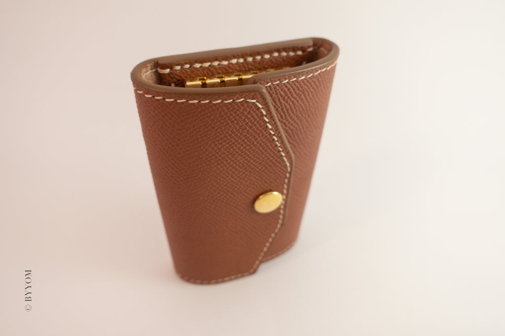 Brown leather wallet with gold accents on a beige background