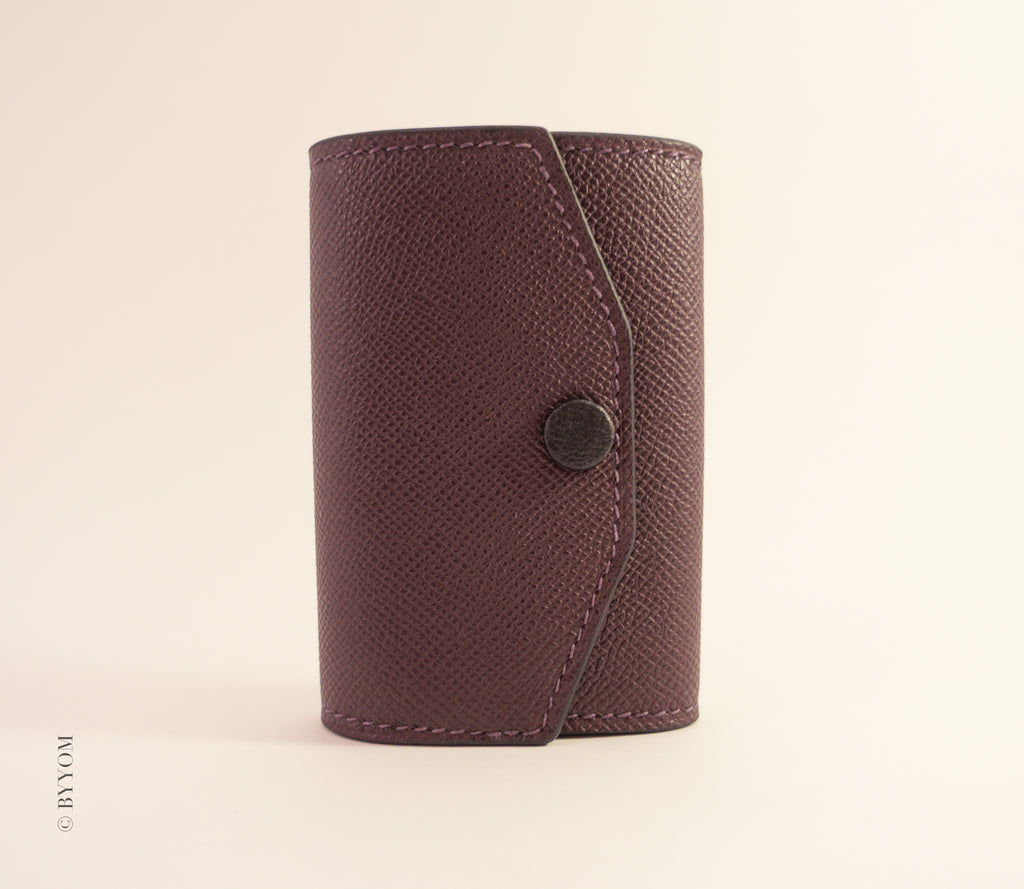 wine color leather wallet with a goat skin covered snap button on a beige background