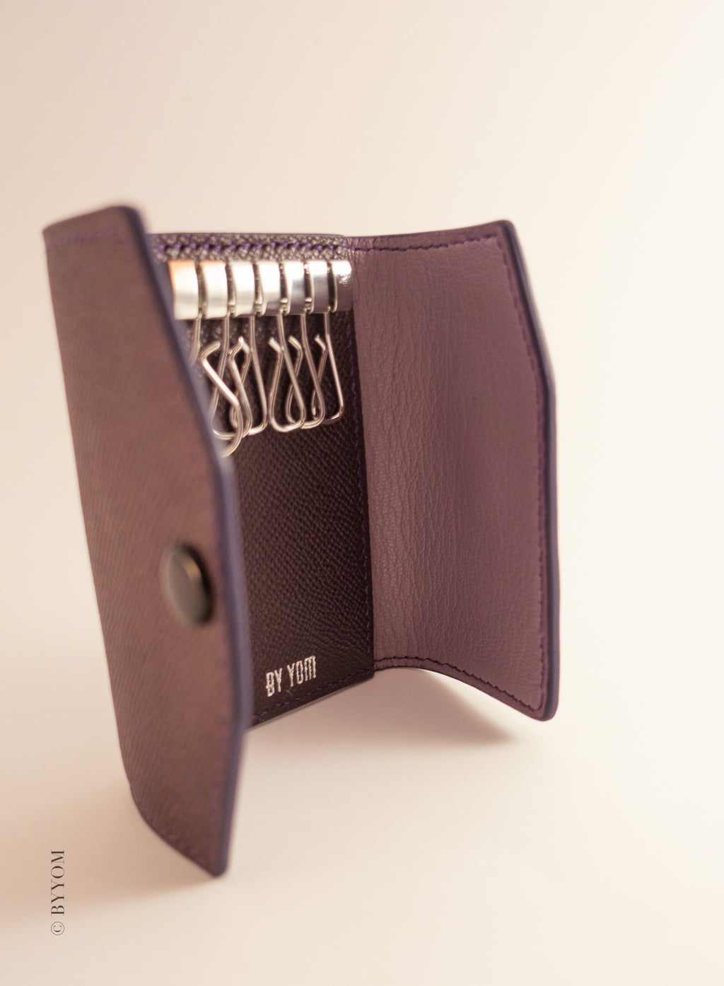 Purple key holder paired with pastel pink interior on a beige background
