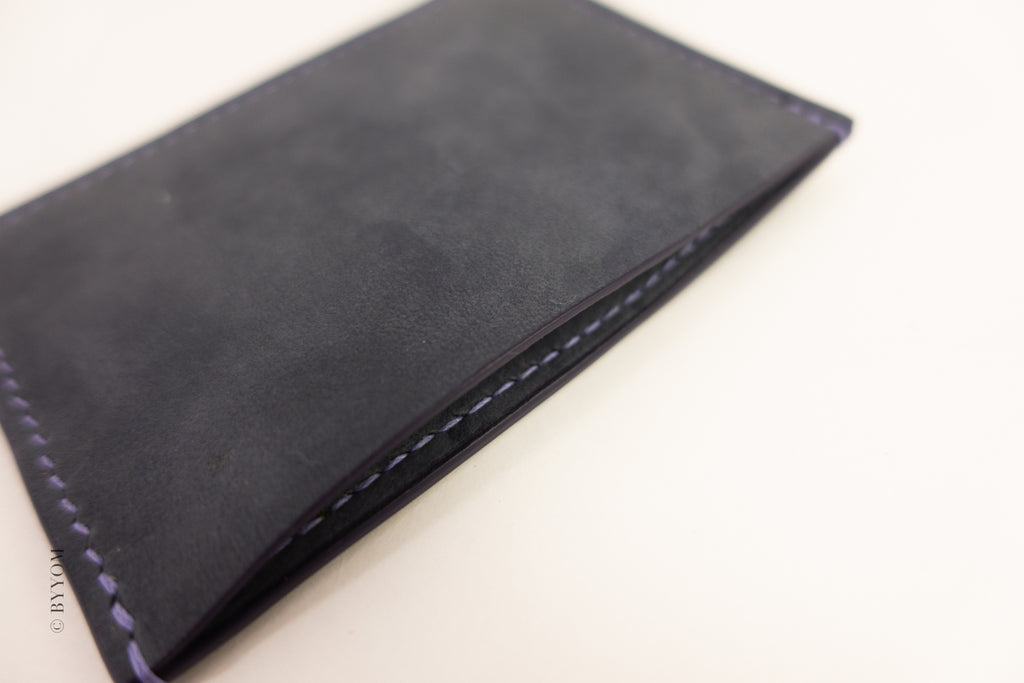 Close-up for back of slim card wallet with visible stitching on a white background