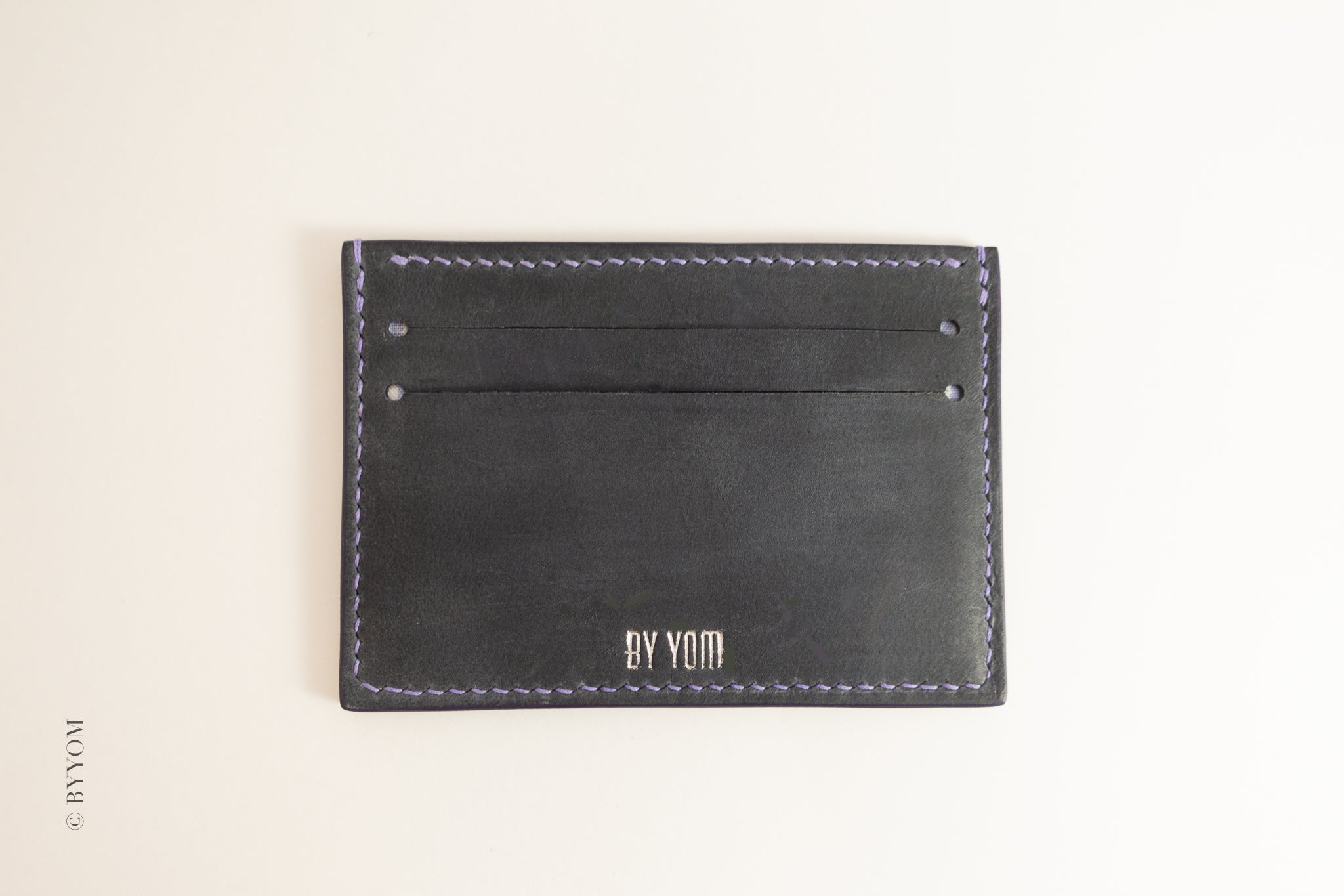 Navy Nubuck leather cardholder with 'BY YOM' branding on a beige background