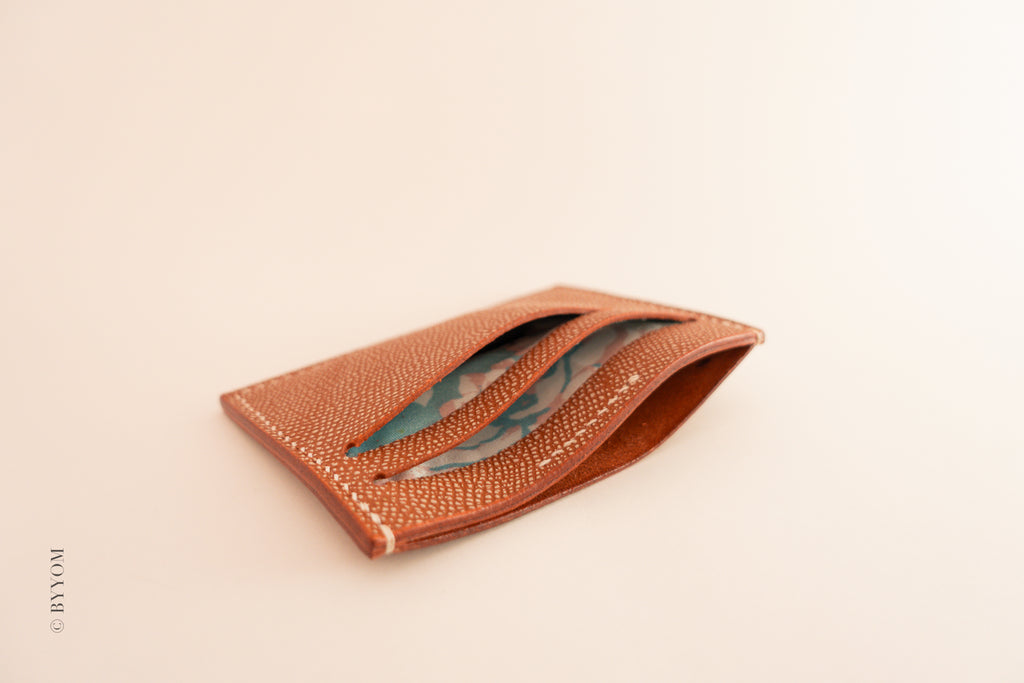 Red leather cardholder showing interior of the wallet on a beige background