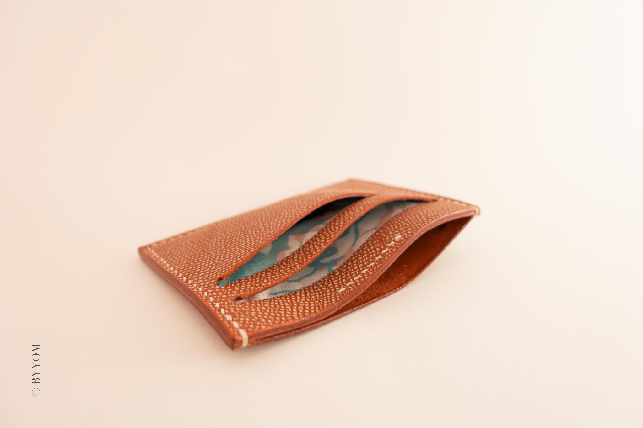 Red leather cardholder showing interior of the wallet on a beige background